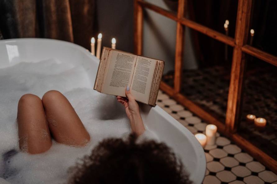 Bride relaxing and reading in a bubble bath