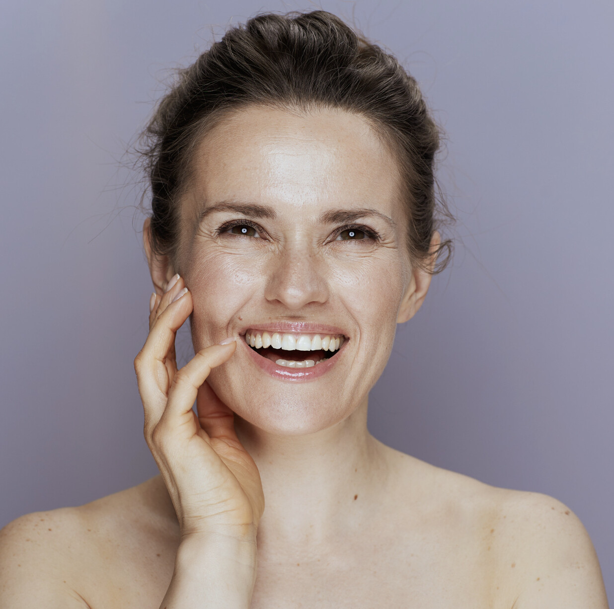 A woman touching her skin that appears to be moisturised 