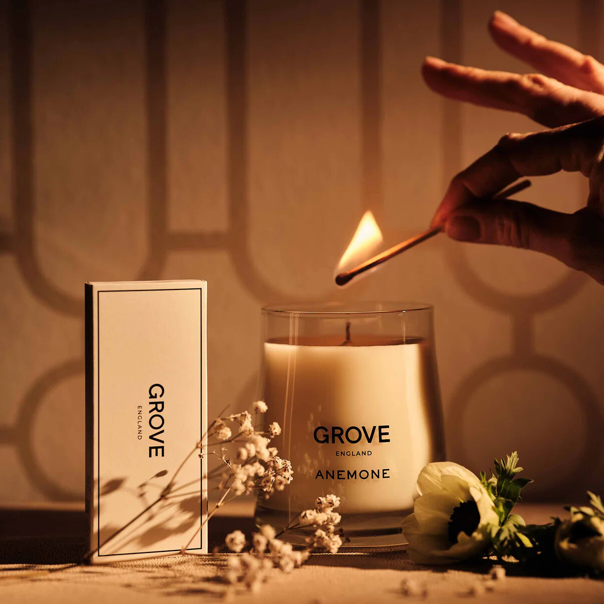 Someone lighting a GROVE England candle