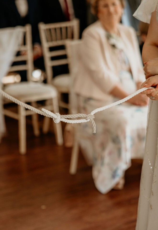 Couple performing a handfasting ceremony with tied rope to tie the knot