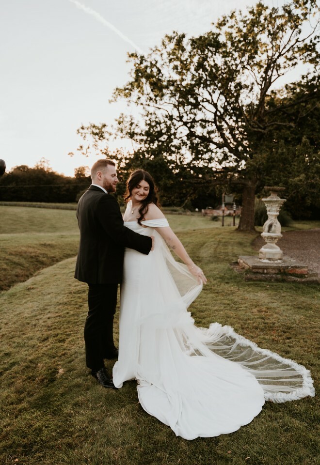 Bride adjusting her flowing cape with the groom