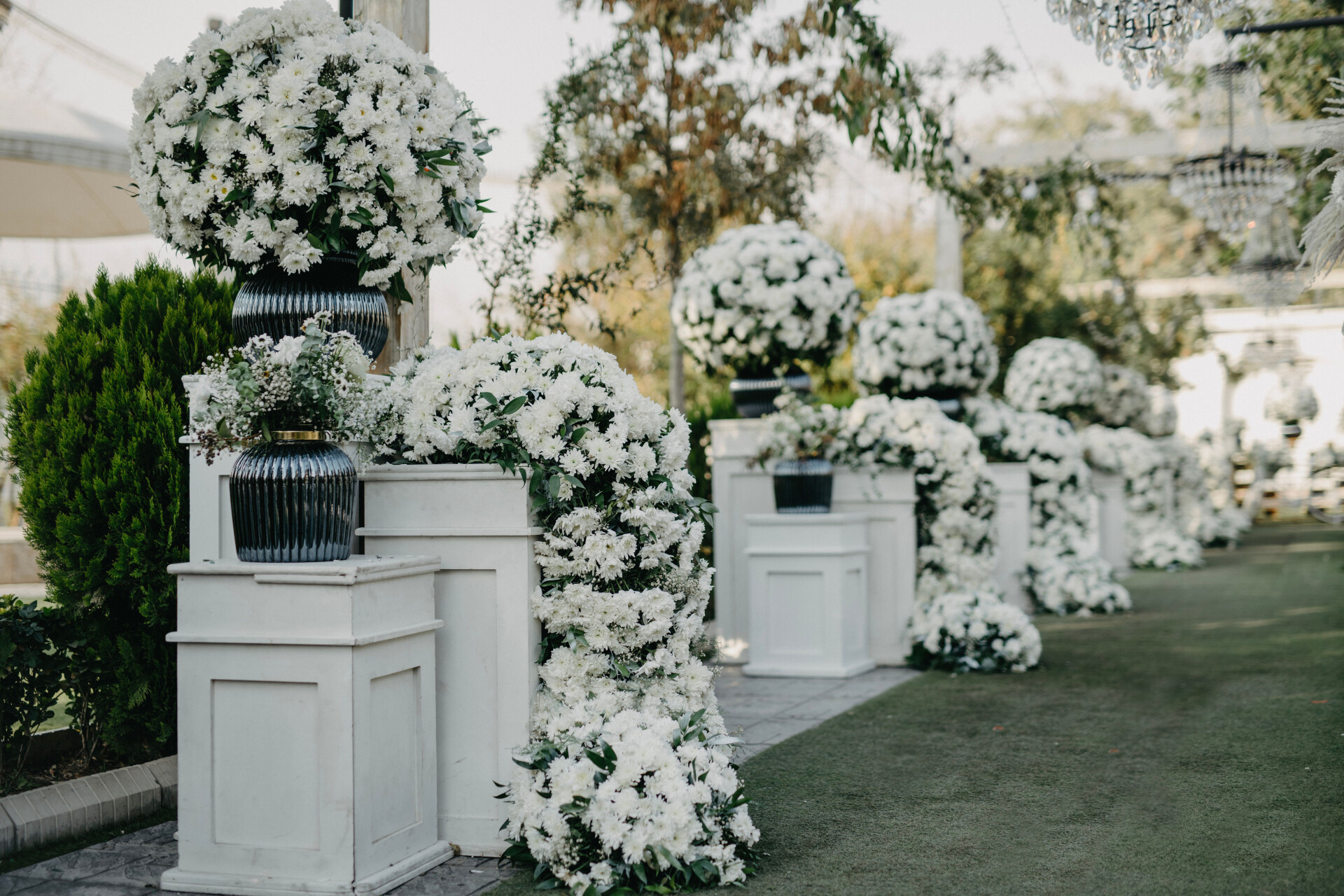 Elegant white floral arrangements creating a dramatic aisle display for a luxury wedding ceremony.