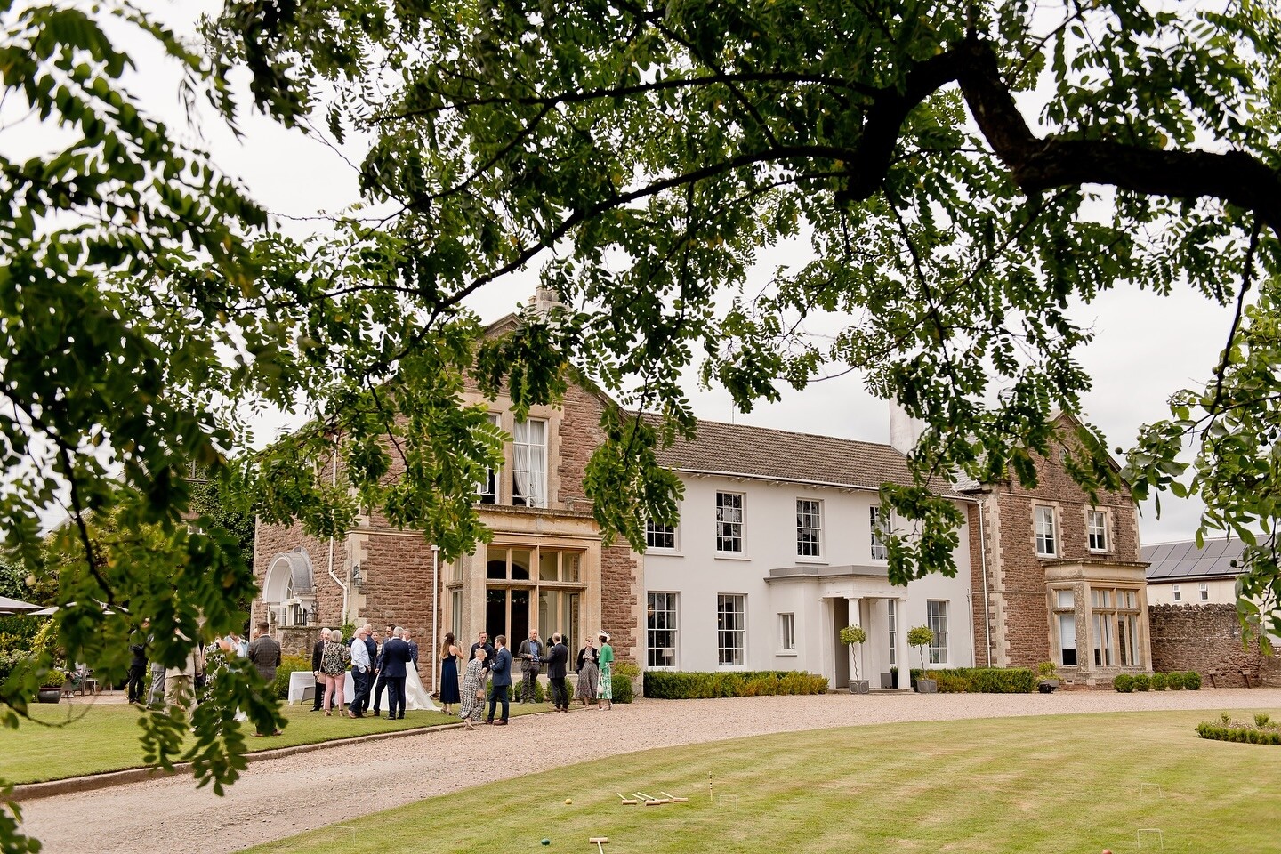 Guests mingle outside Glewstone court country house during a wedding