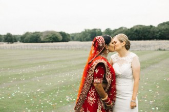 Brides kissing in lawn of Rise Hall
