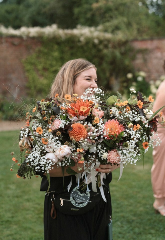 Wedding coordinator, Georgina Rose Events, carries bridesmaids bouquets to be reused on wedding breakfast tables