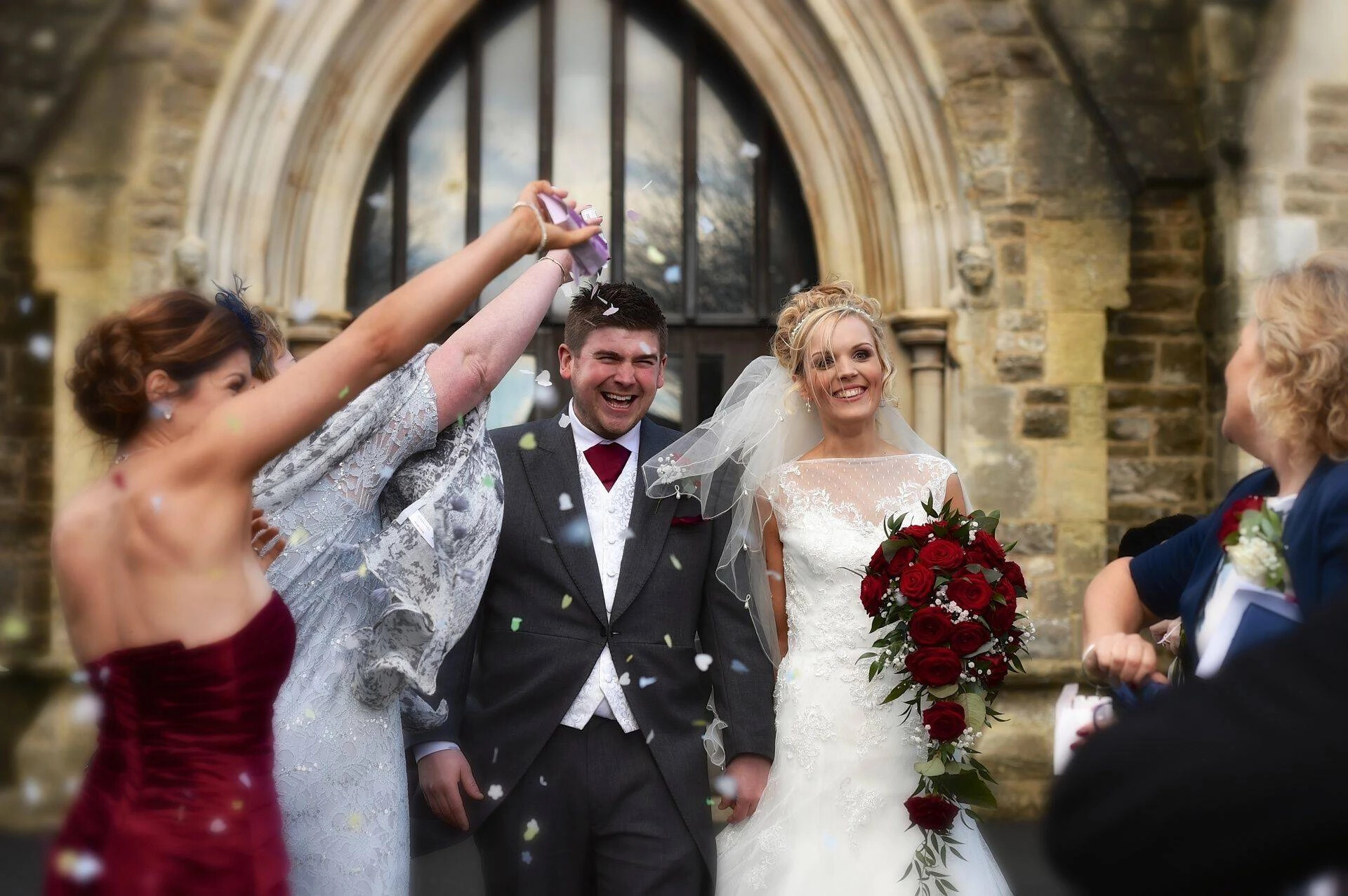 Bride and groom celebrating outside the church as confetti is thrown. Captured by James Donovan Photography in Wiltshire.