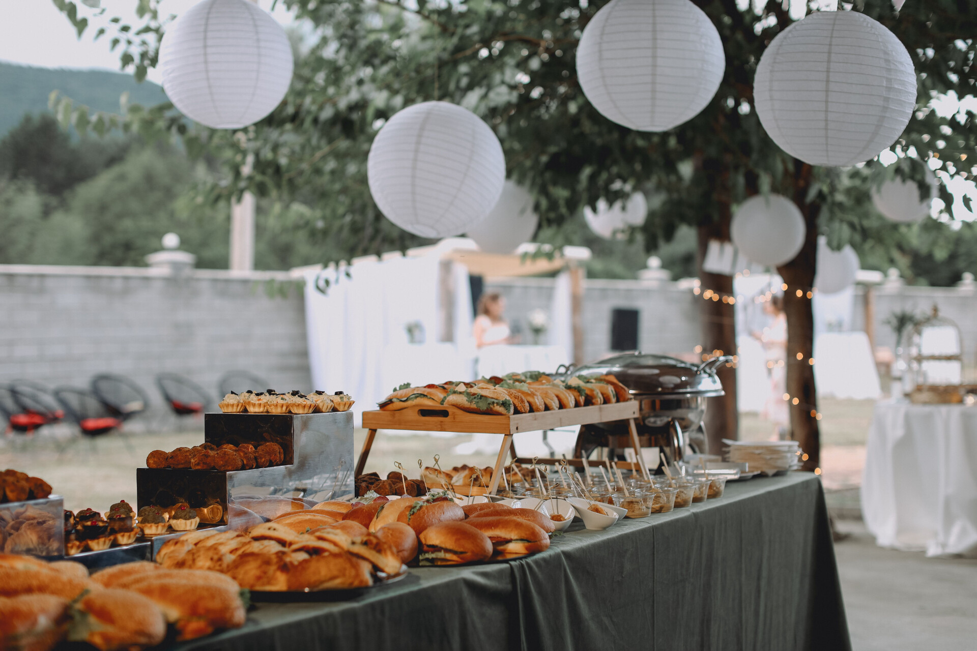 Wedding buffet featuring sharing platters, sandwiches and desserts at an outdoor wedding reception.