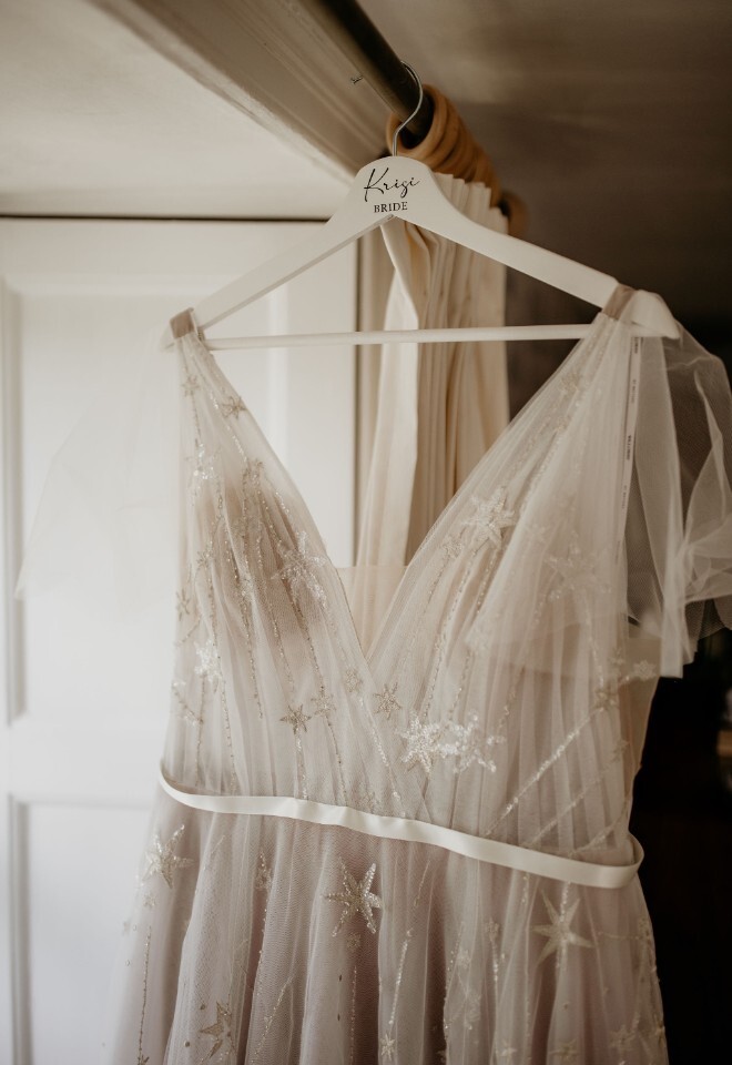 Wedding dress with star embroidery hanging on a personalised “Krisi Bride” hanger.