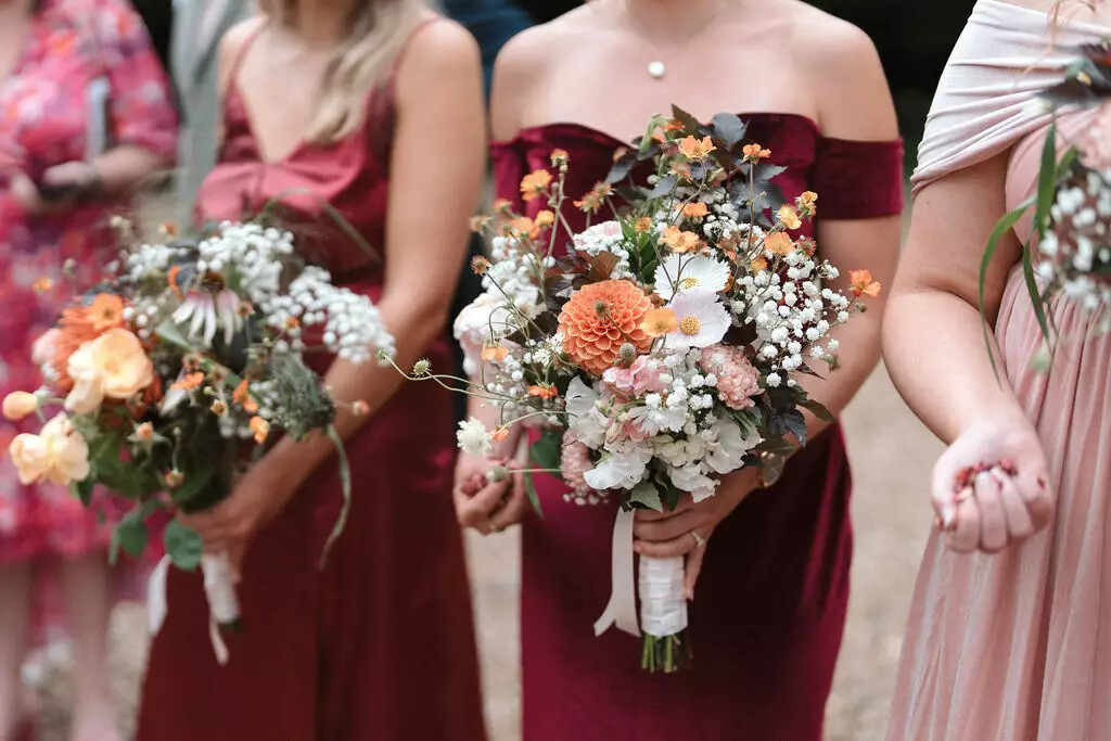 Bridesmaid in a red dress holding a bouquet with summer flowers