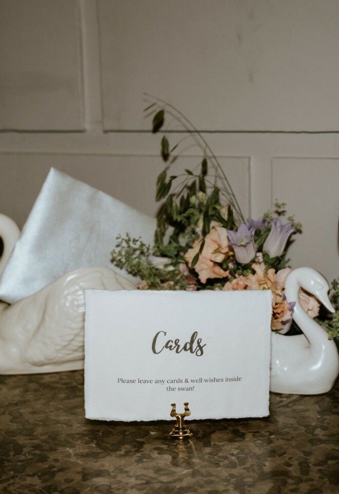 Two ceramic white swans filled with cards from wedding guests
