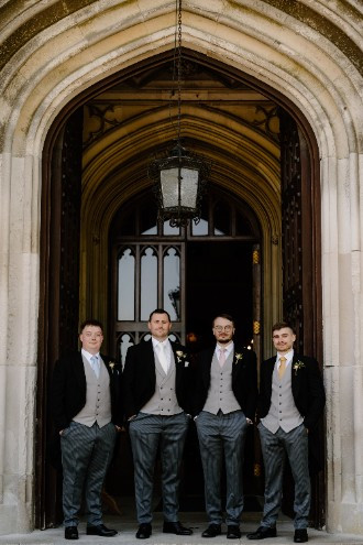Groomsmen under an archway in front of Ashridge House