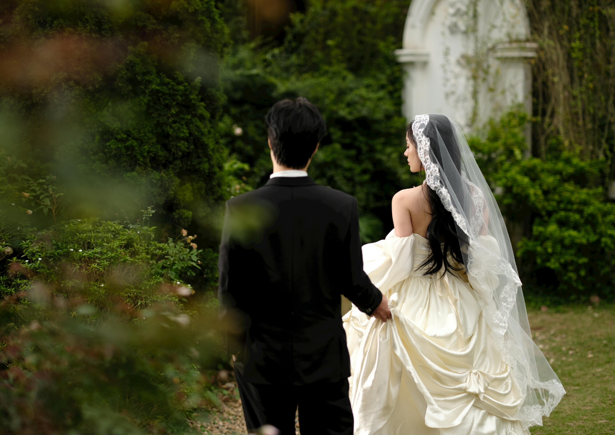 A couple in wedding dress and suit, walking round venue grounds