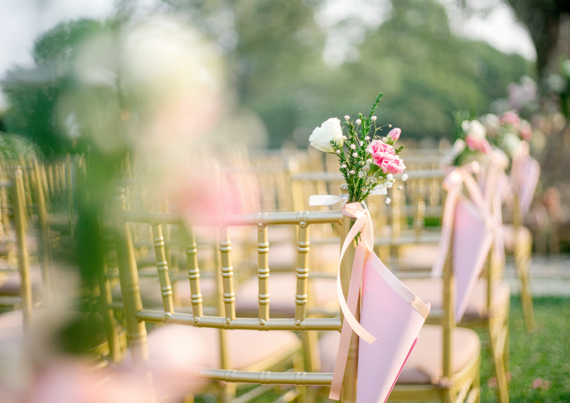 A ceremony with chairs, focused on a chair with flowers on