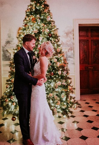 Bride and groom in front of Christmas tree at Hedsor House wedding venue