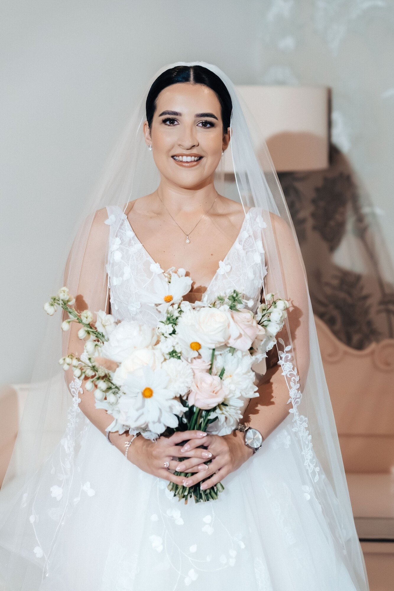 Bride holds her hand tied wedding bouquet with summer flowers
