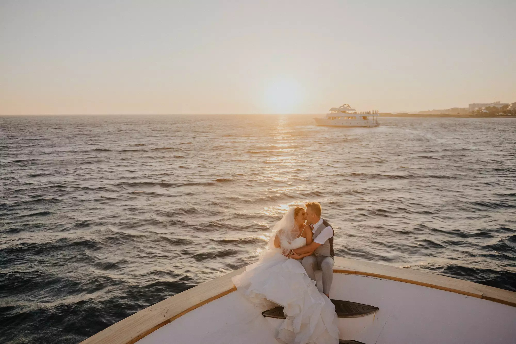 A couple sat on the Bow of a boat in the sunset