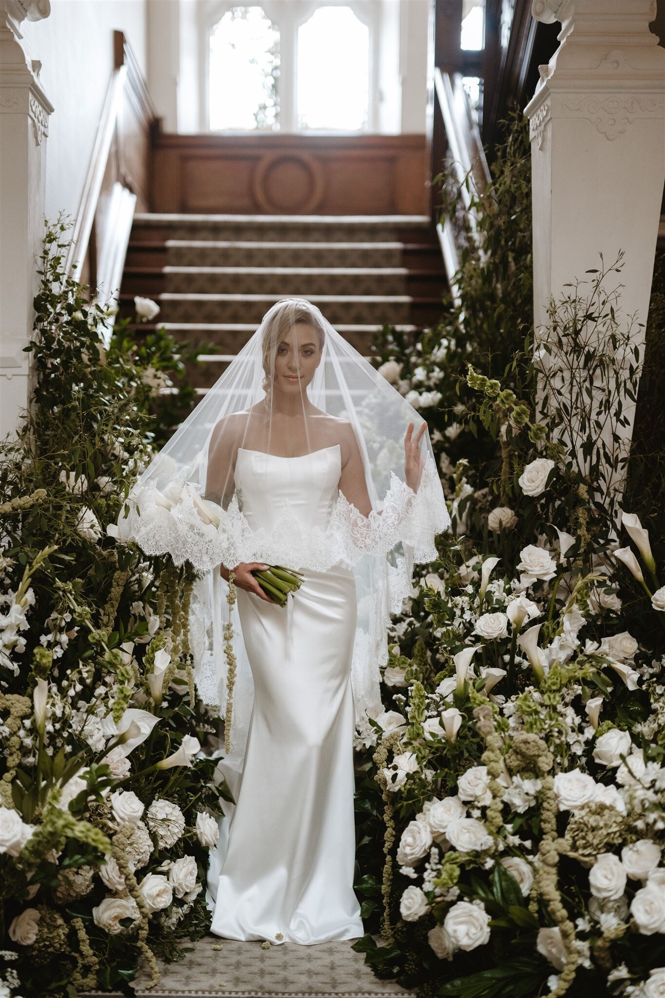 Bride stands at the alter holding a presentation wedding bouquet with calla lillies and white flowers