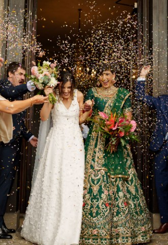 Ana and Satveer walking out of Davenport House, with confetti being thrown at them.
