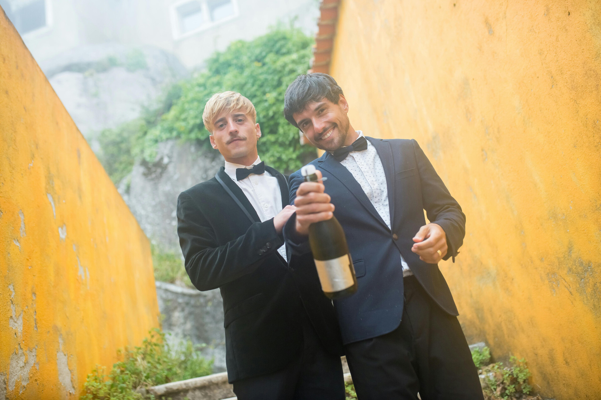 Groom and groom couple celebrating their wedding day with a bottle of champagne