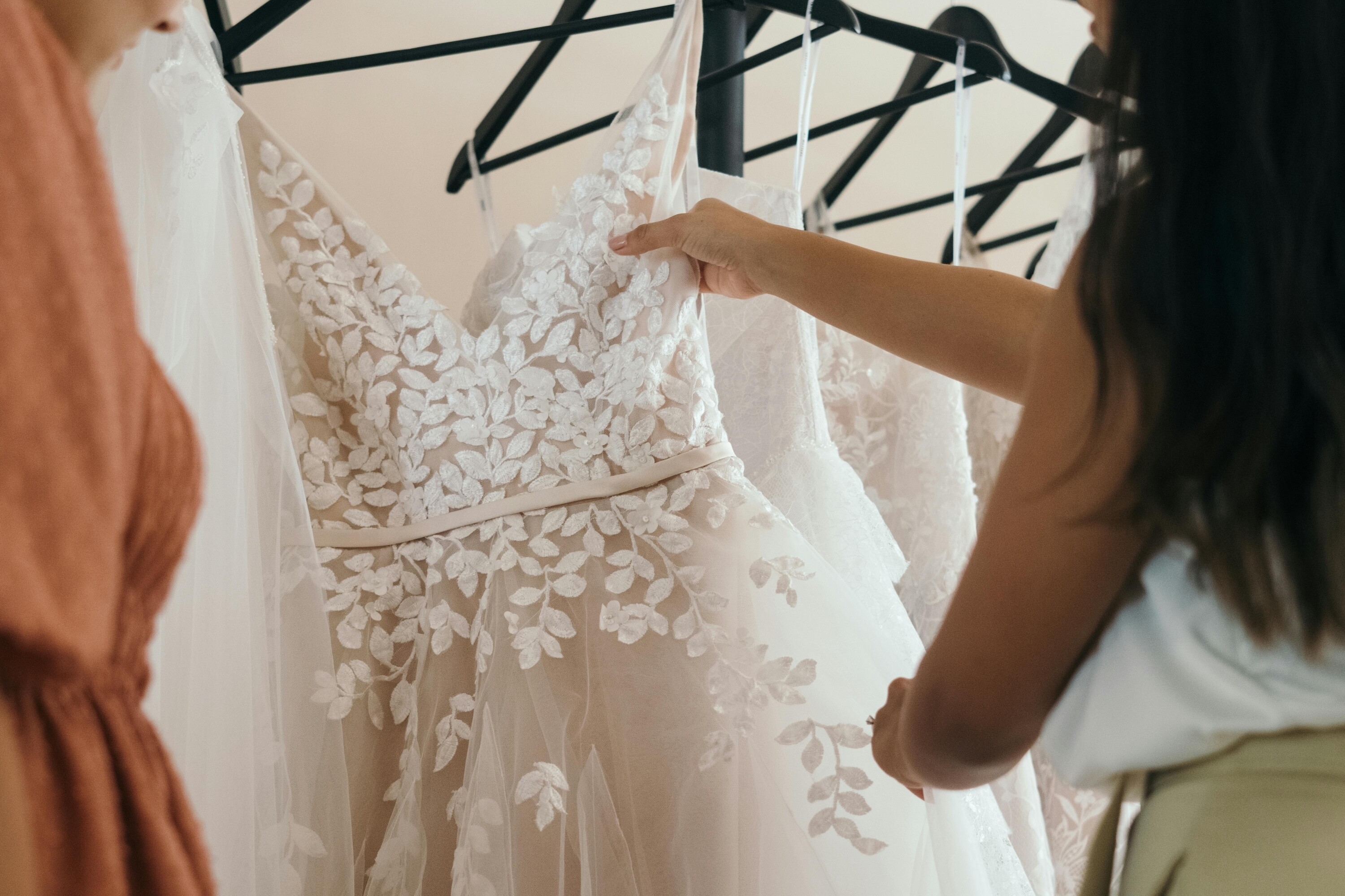 person picking a floral wedding dress of a rack in a shop