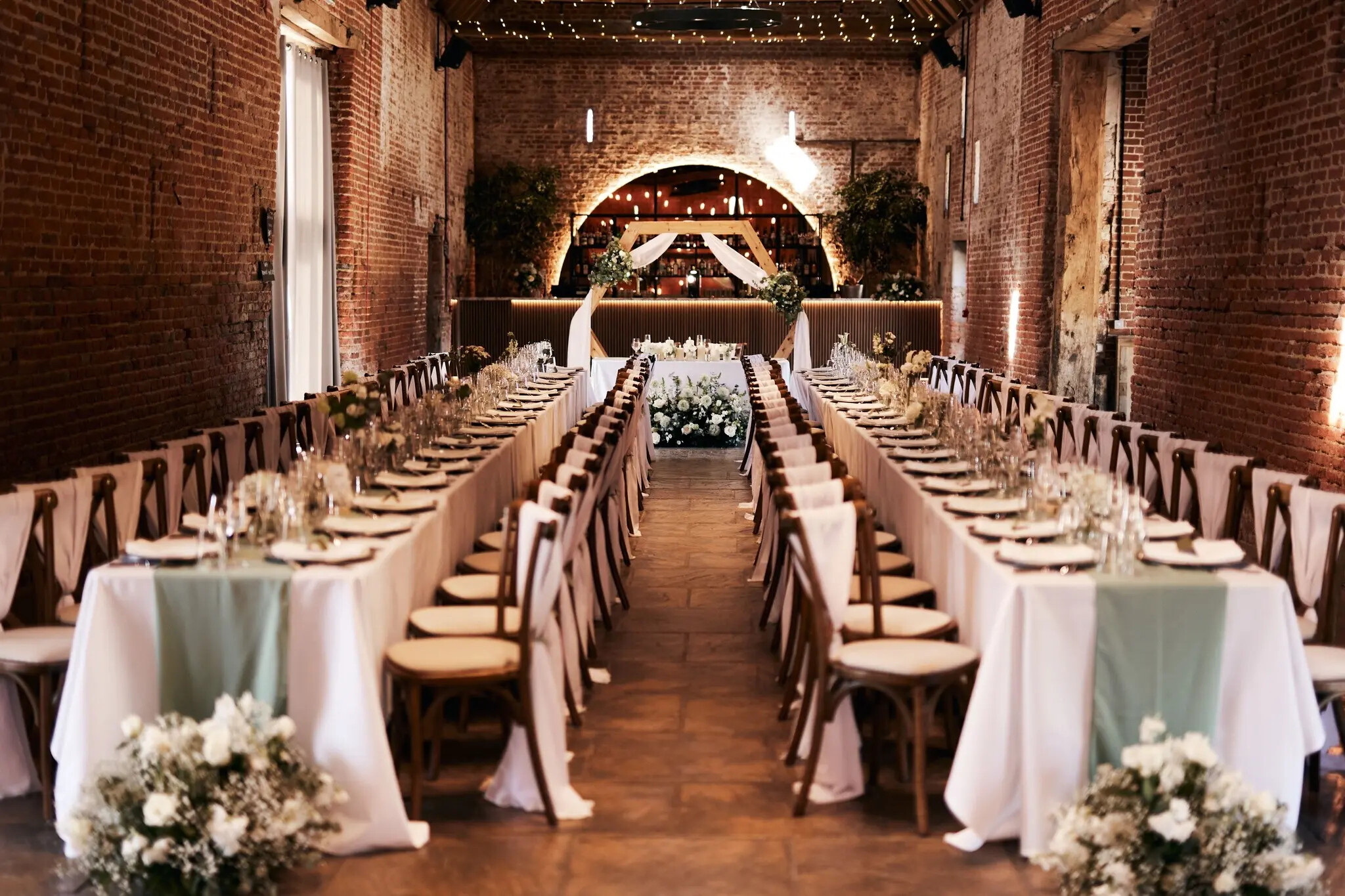 Interior barn of Copdock Hall set for a wedding breakfast with tressel tables