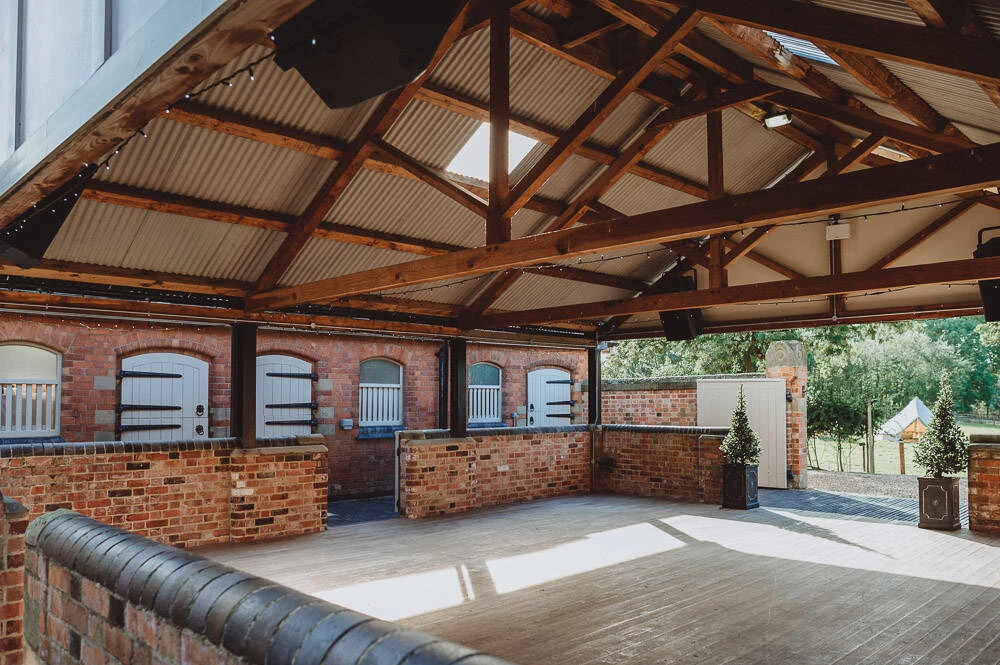 Interior of The Hall Barns at Prestwold in Leicestershire, featuring exposed timber beams, brick walls and an open reception space overlooking the grounds.