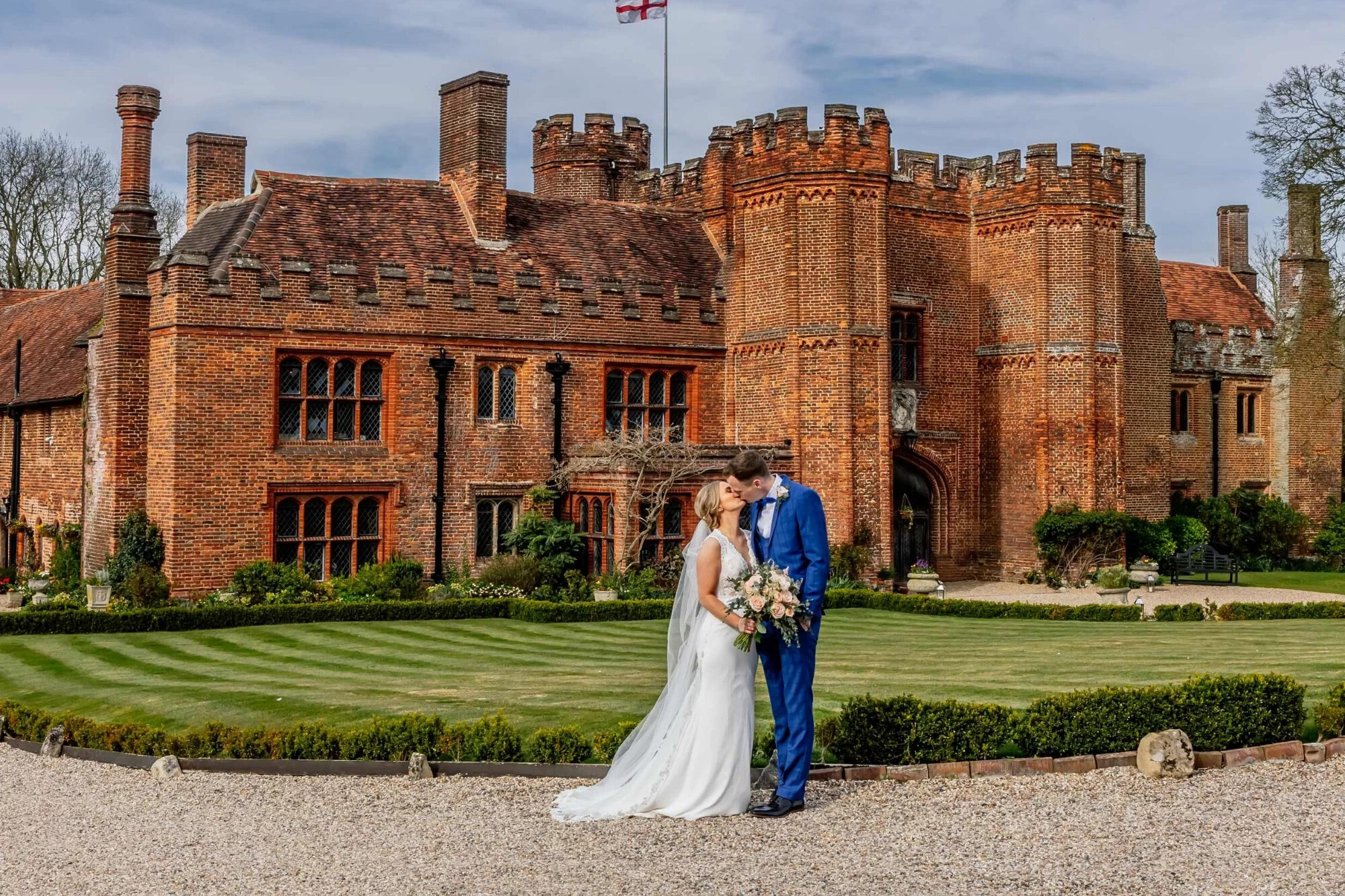 Newlyweds kissing in front of Leez Priory Castle wedding venue