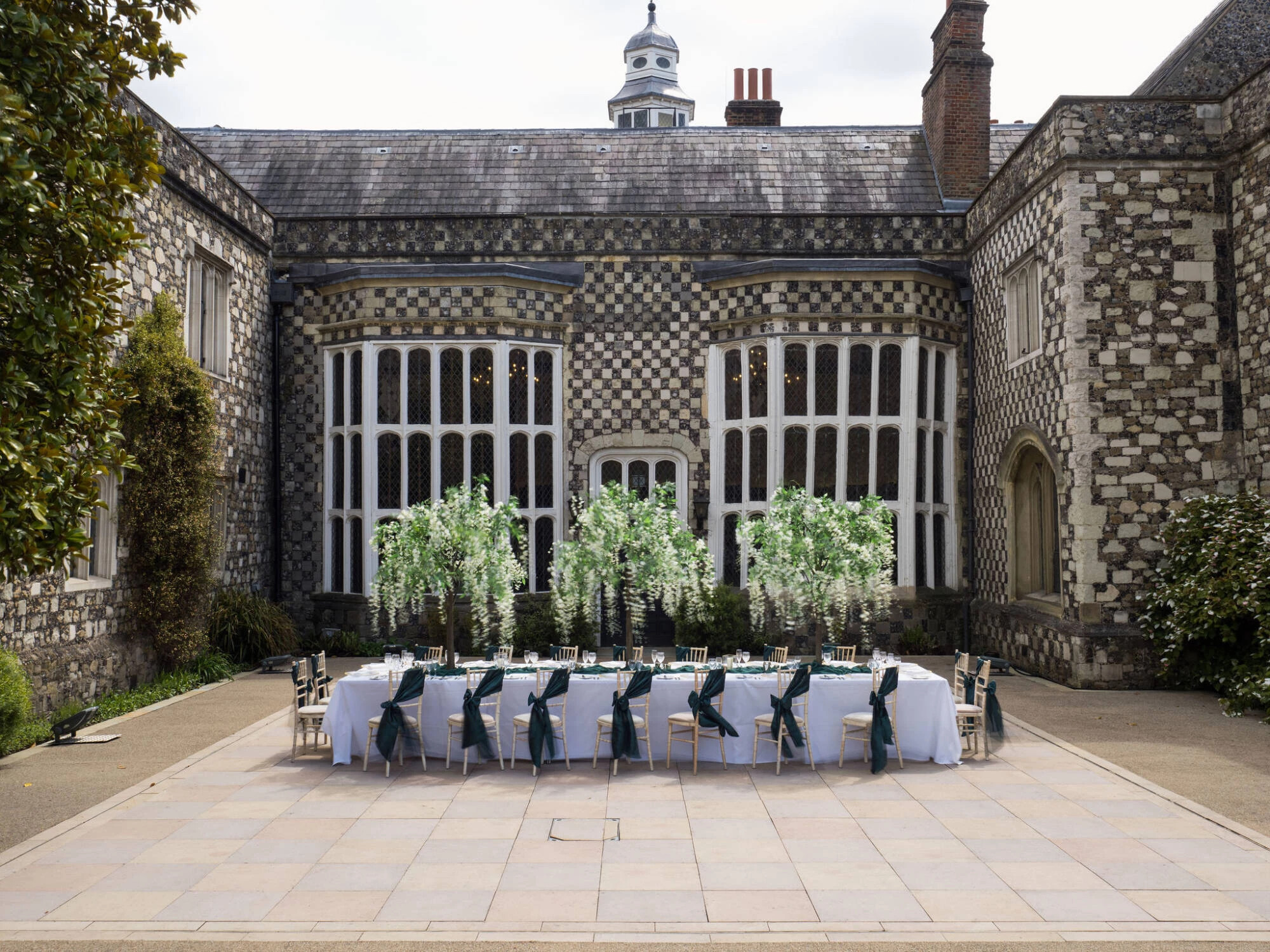 The courtyard at Hall Place & Gardens in Kent, with a wedding breakfast trestle style table and chairs set up outdoors.