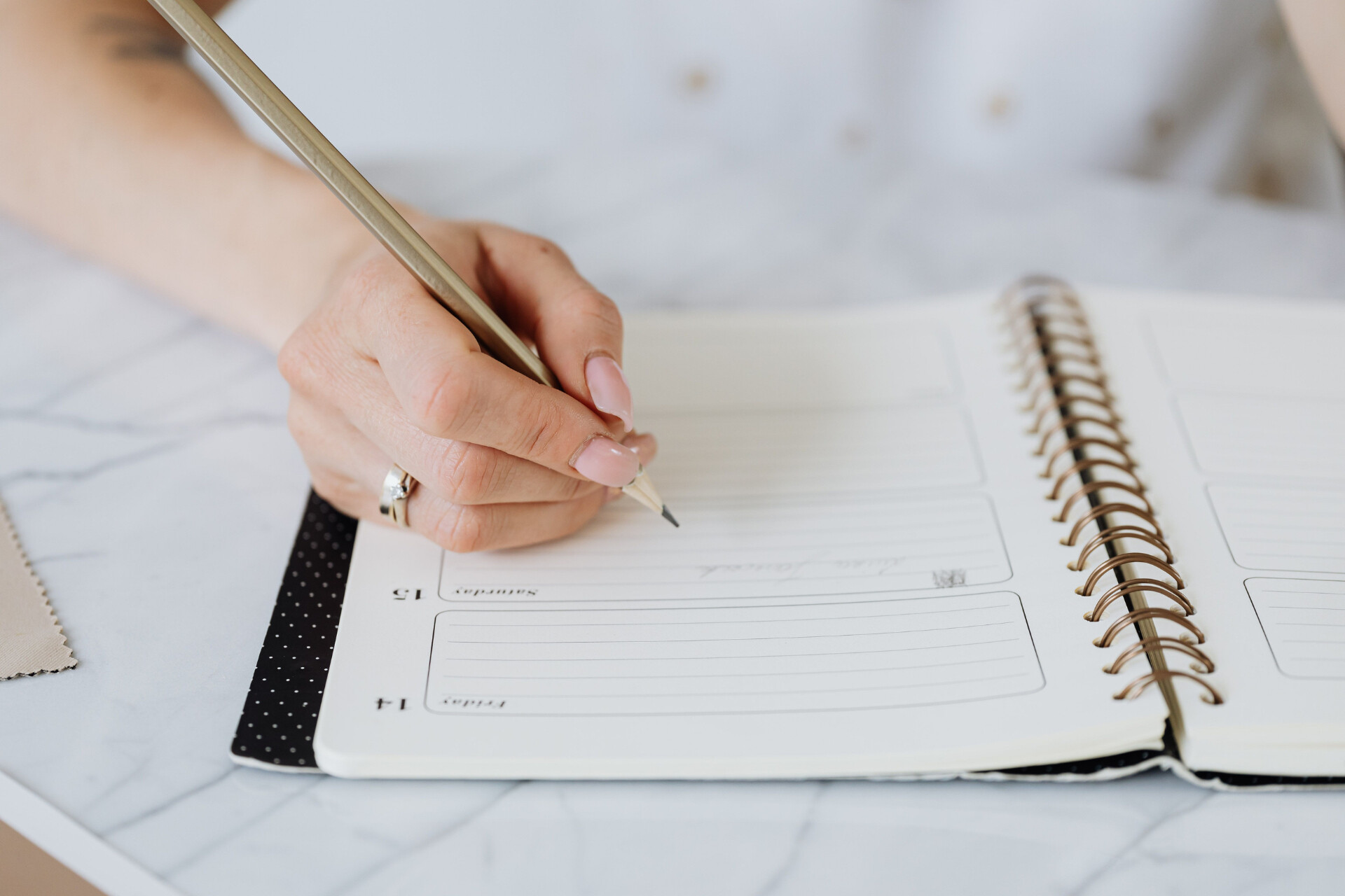 Bride-to-be writing in a wedding planner while organising the details of her celebration.