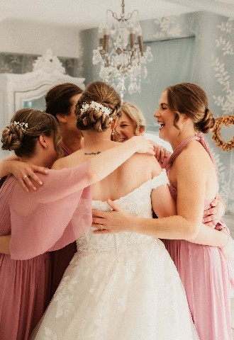 Bride and bridesmaid hug in getting ready room at Southdowns Manor West Sussex