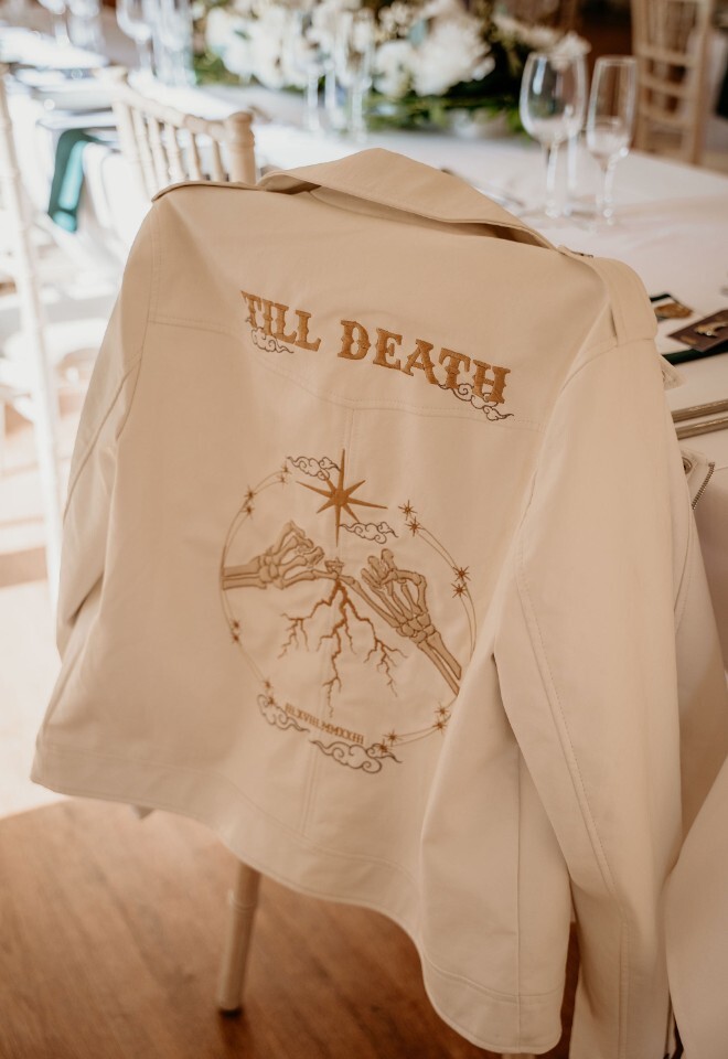 Custom “Til Death” embroidered bridal jacket draped over a chair.