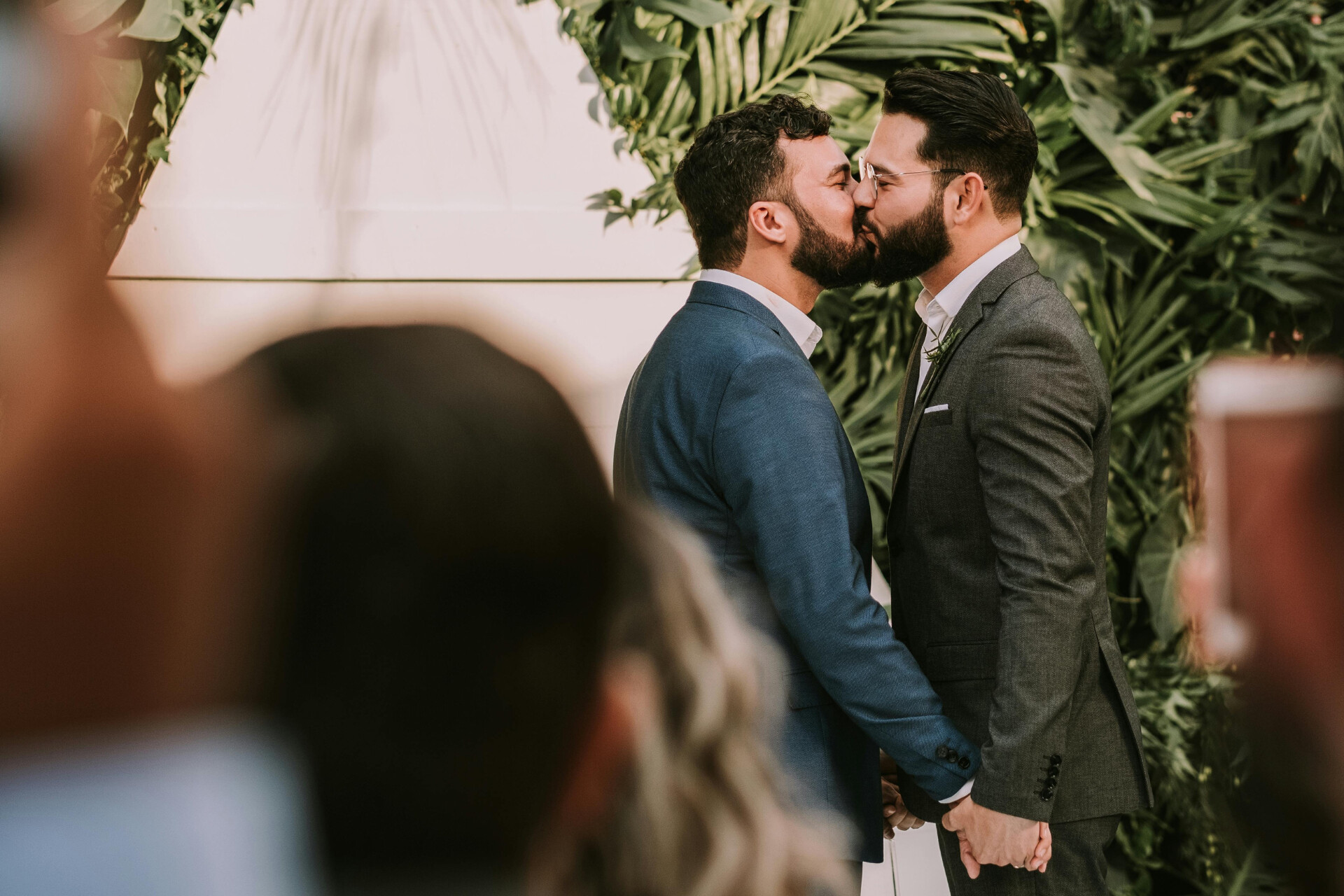 Groom and groom couple sharing their first kiss during a same-sex wedding ceremony