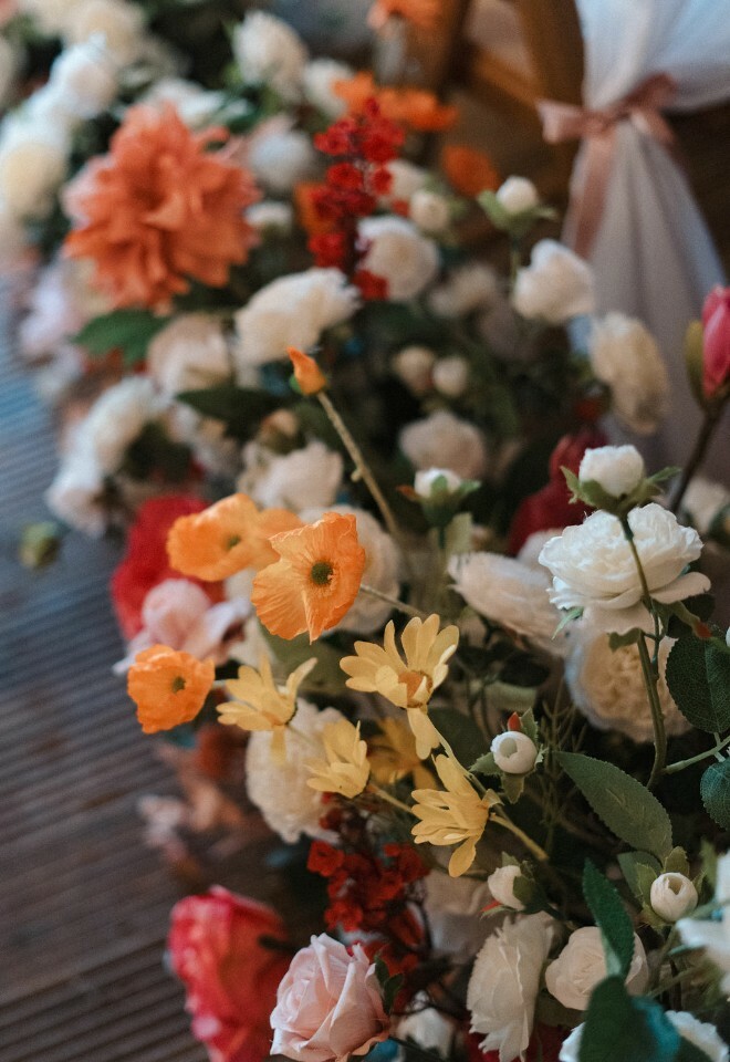 Orange, pink, yellow and white faux flower arrangements used in wedding ceremony decor