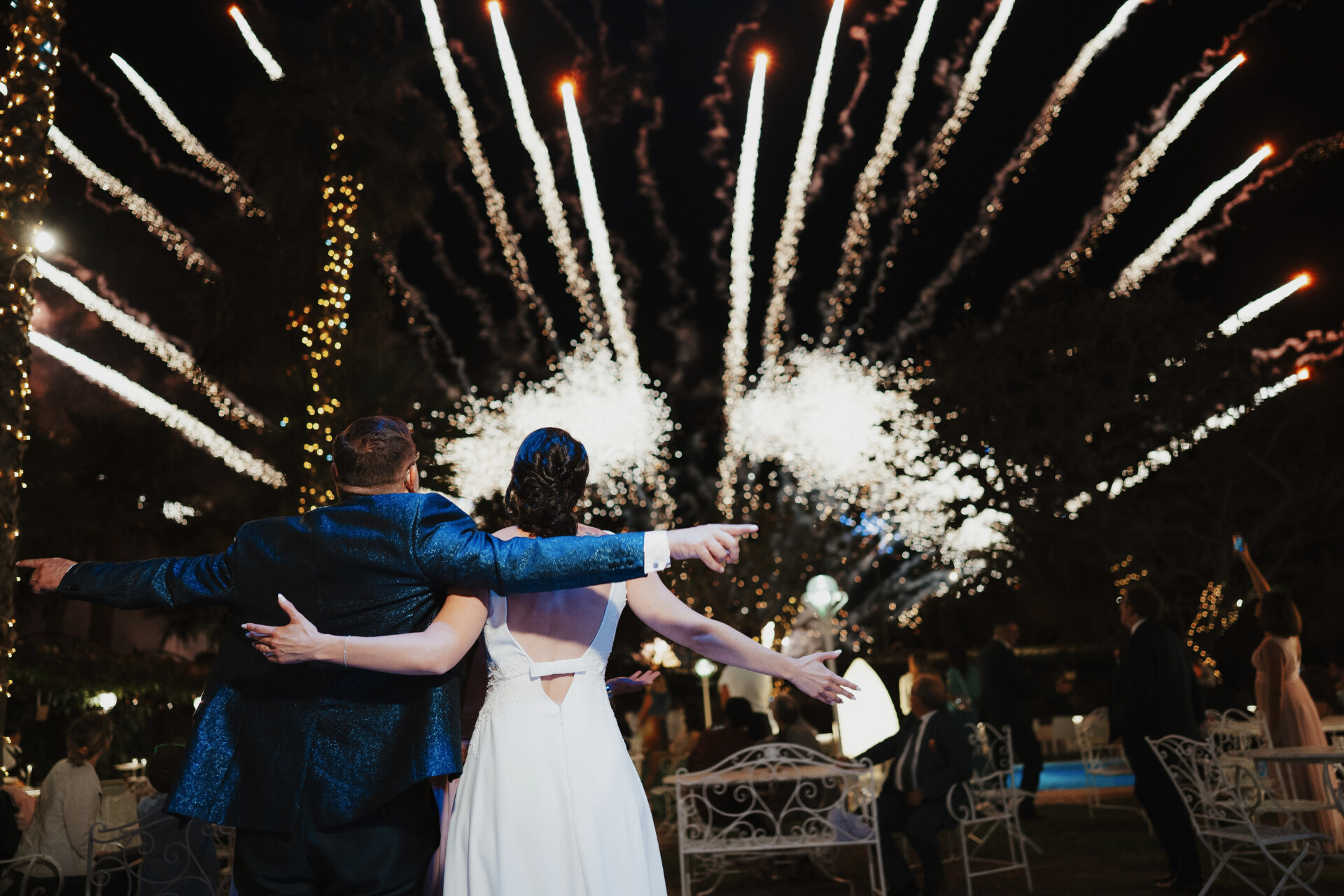 Newlyweds watching a spectacular fireworks display during their wedding reception.