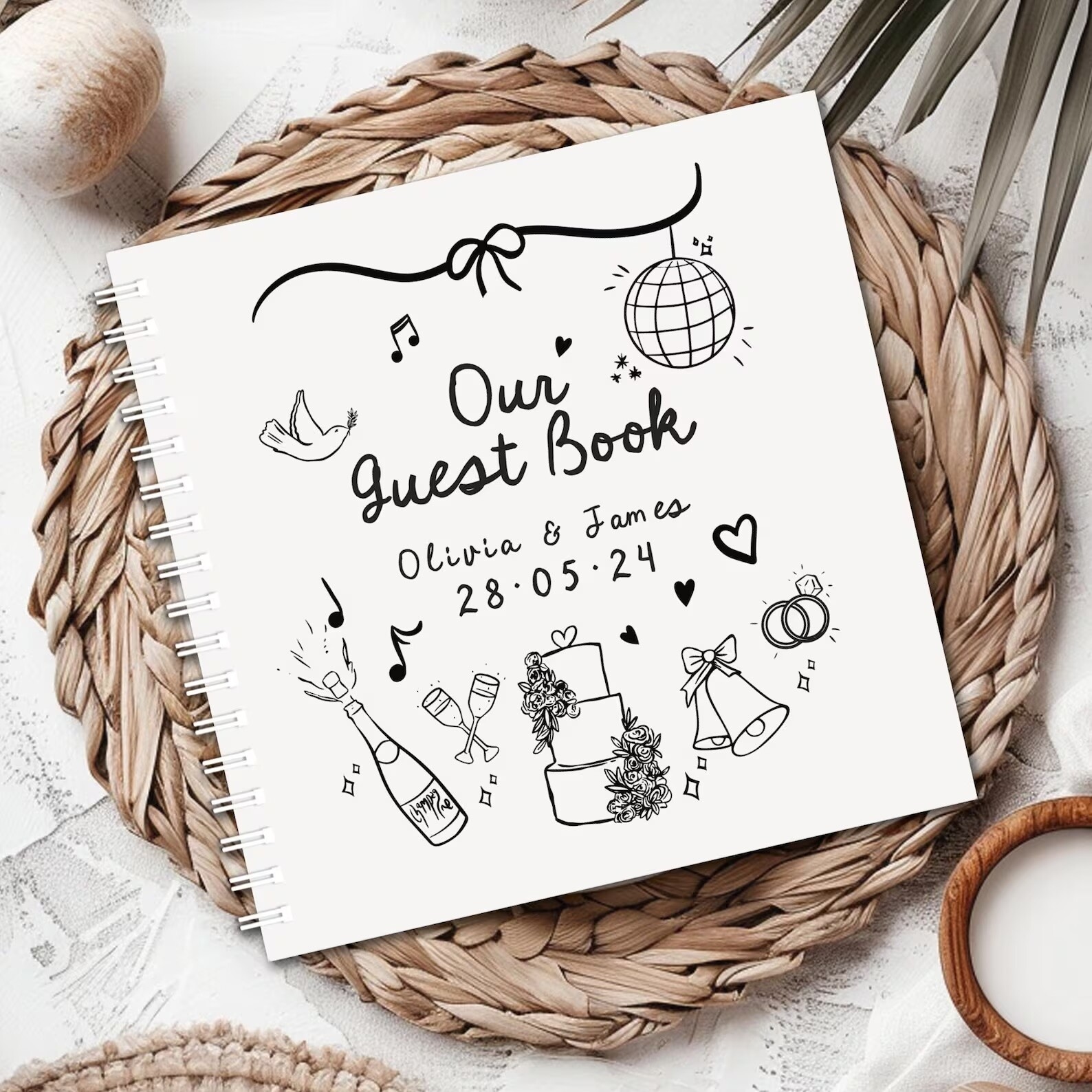 white wedding guestbook with doodle details of wedding items and couple name and wedding date written on the front