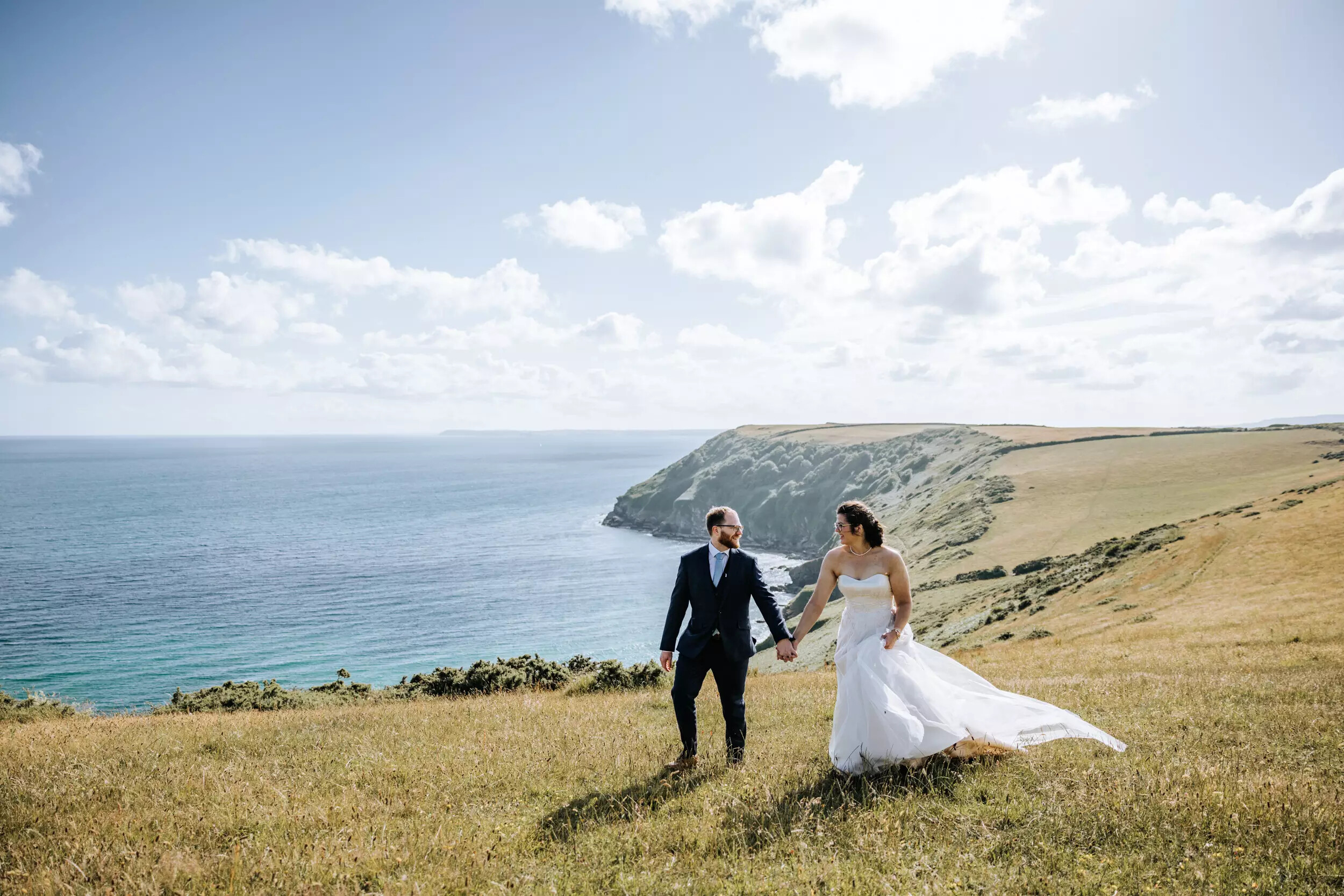 Bride and groom walk along the Cornish coastline