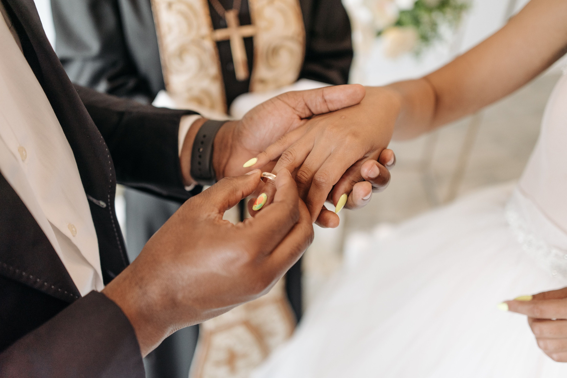 Groom placing wedding ring on brides hand infront of wedding officiant