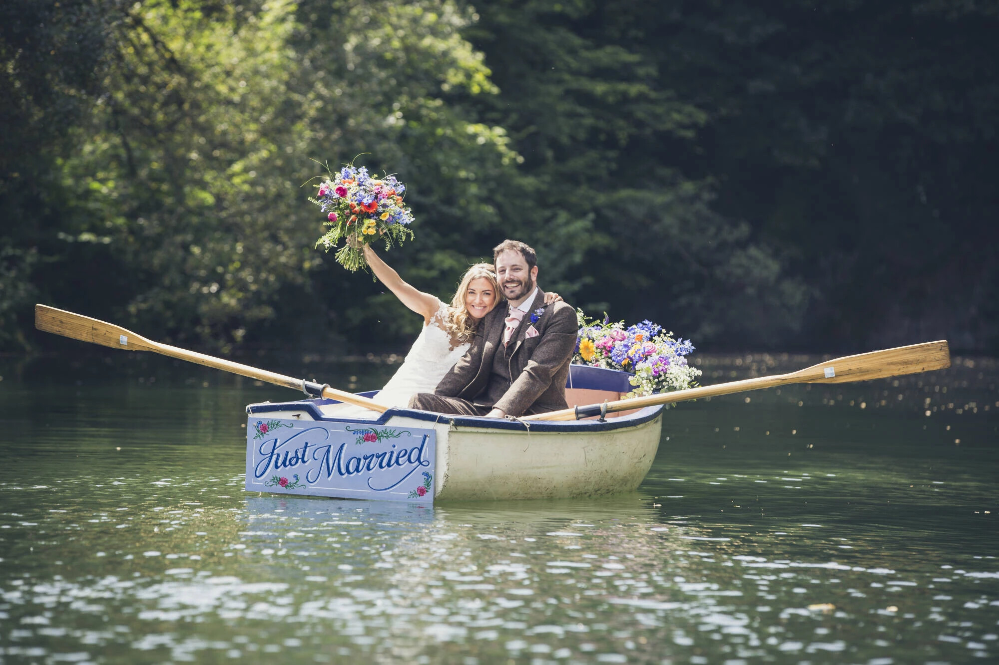 Bride and groom rowing in a little boat which reads "just married" on the back