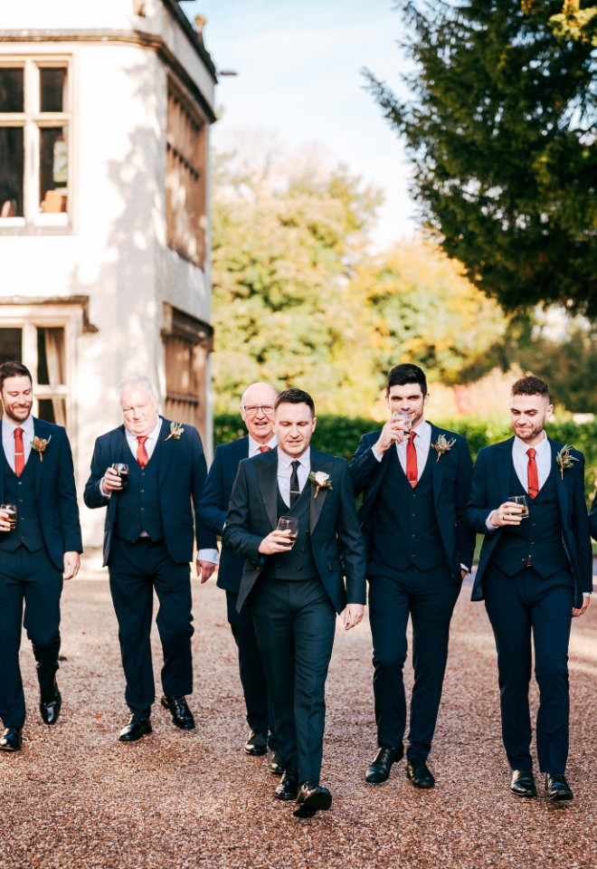 Groomsmen all walking together outside Mitton Hall