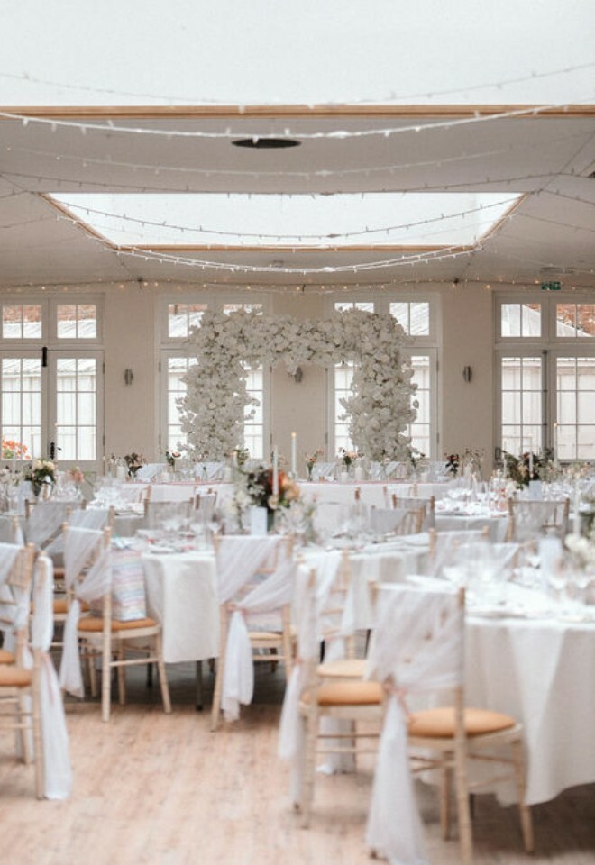Elmhay Park orangery set for wedding breakfast with pink and white decor and faux flower arch