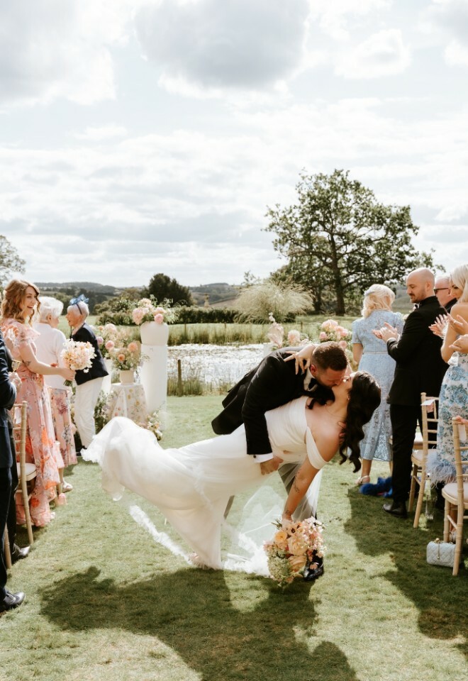 Bride and groom dip kiss at the end of the aisle