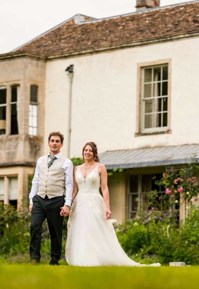 wedding couple posing in the garden with the venue in the back