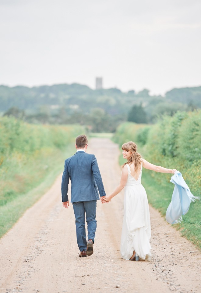 Bride and groom walking down lane at Barn Drift wedding by Stuart Wood