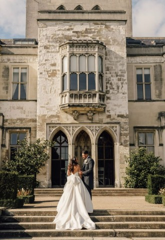 Bride and Groom stood on the steps in front of Ashridge House