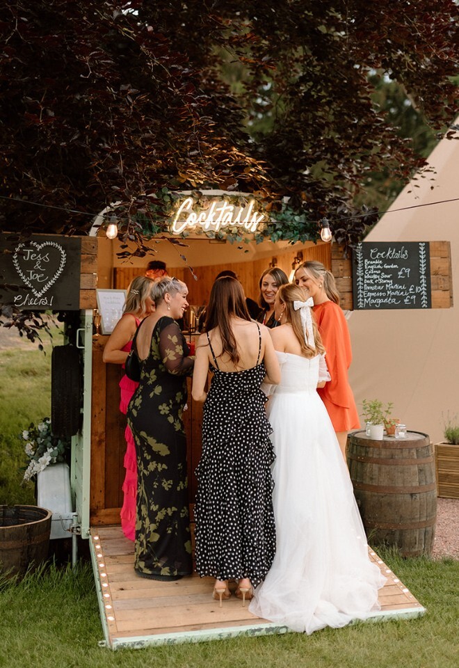 bride with bridesmaids having a cocktail at tipi wedding venue