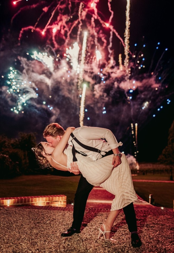 couple kisses during fireworks at wedding reception