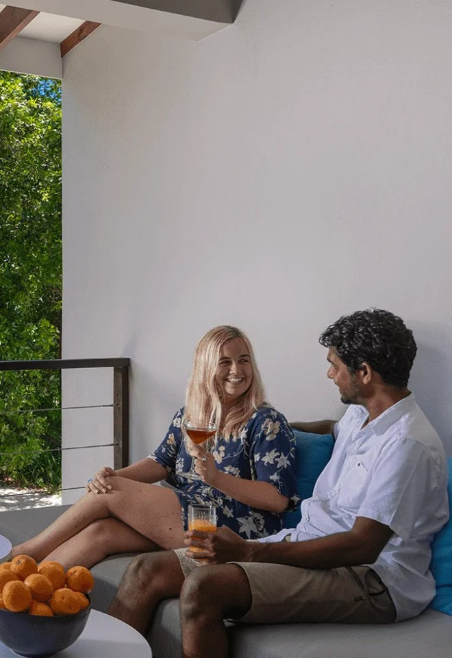 Wedding couple enjoying drinks on a private Maldives villa terrace, showcasing bespoke honeymoon experiences by Mantas & Herons.
