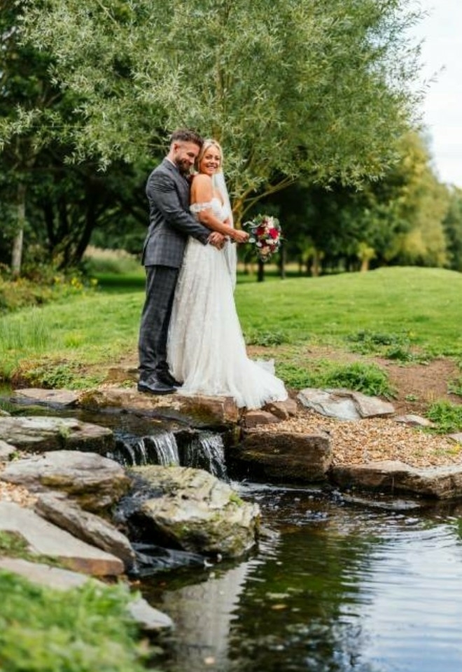 Bride & Groom hugging overlooking the waterfall feature- Sprowston Manor Norwich