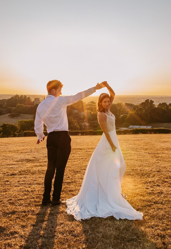Relaxed bride and groom dancing in the Cotswolds countryside, with natural golden hour wedding portraits