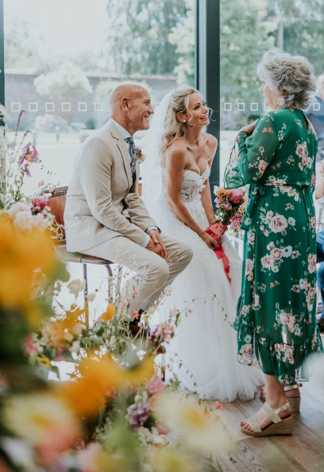 Norfolk celebrant in a green dress having a moment with her bride and groom during the ceremony